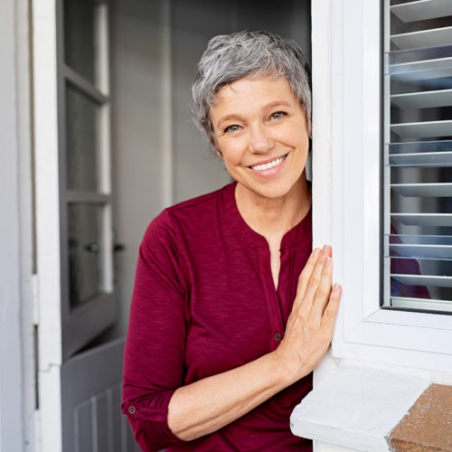 Woman Leaning Against Door Frame Smiling At Camera